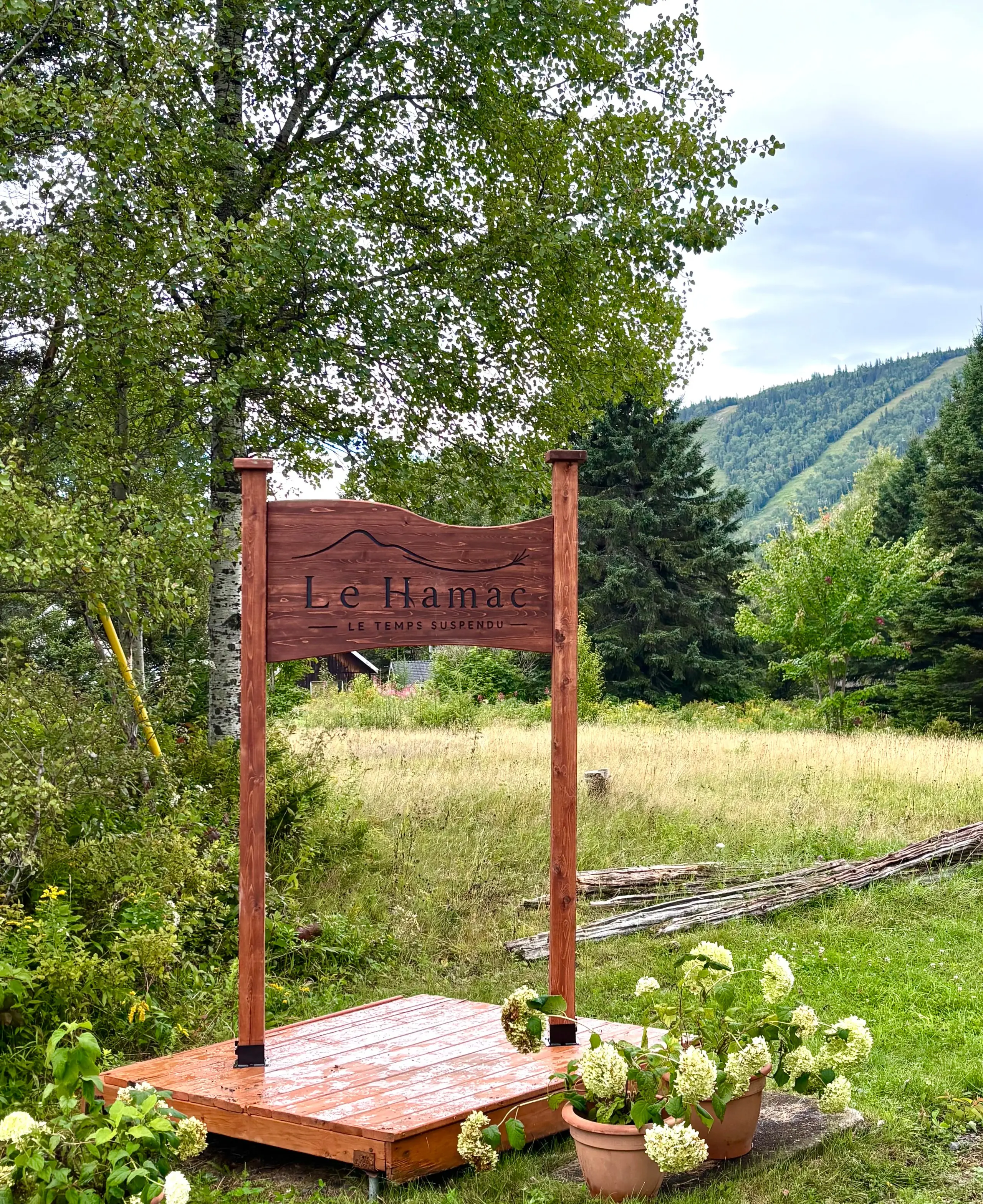 L’enseigne de bois du Hamac - le temps suspendu, devant la montagne de Charlevoix