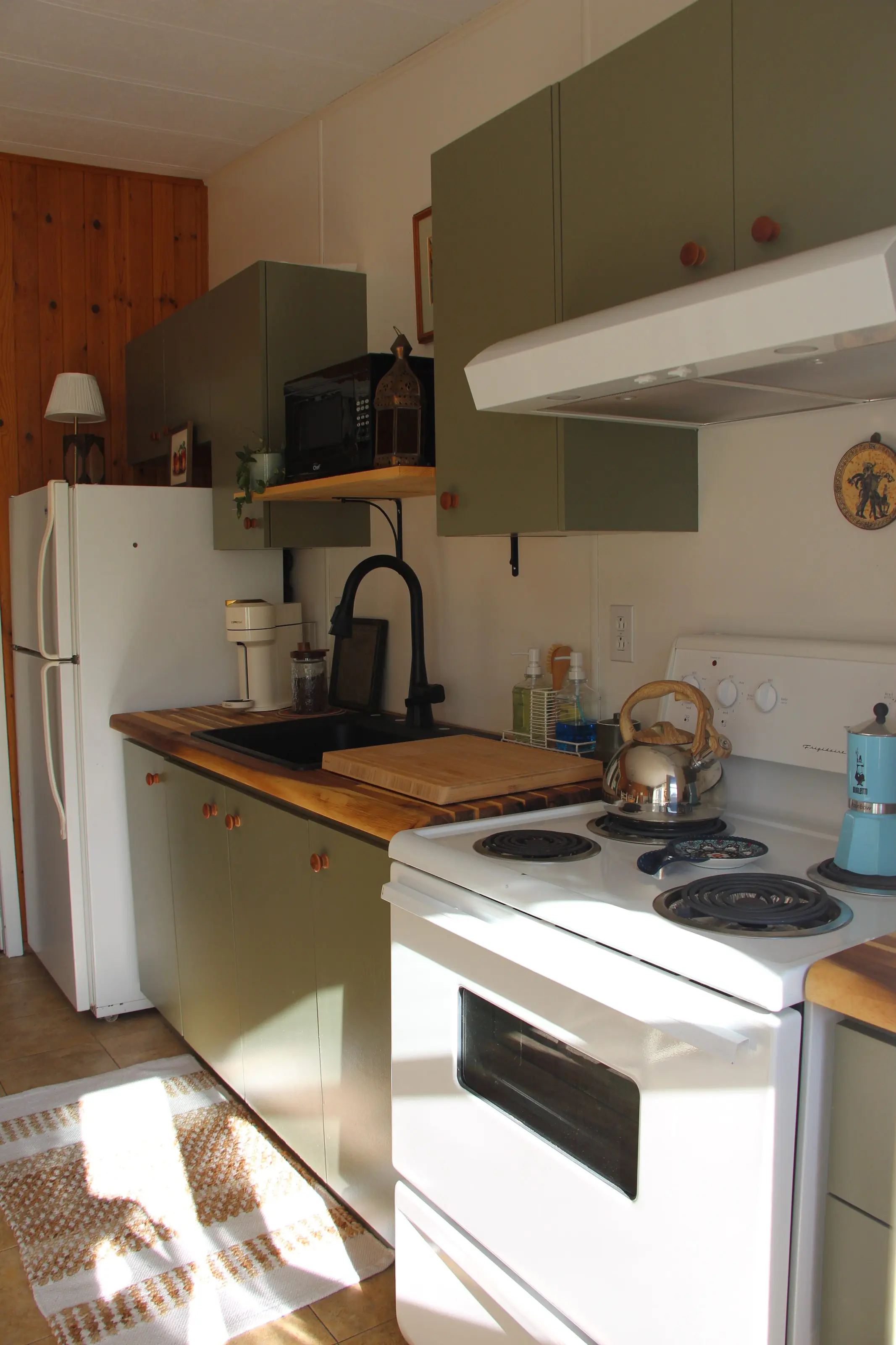 La cuisine aux armoires vert olive, baignée de soleil du matin